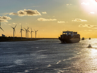 Cargo ship passing wind turbines at sunset in Maasvlakte