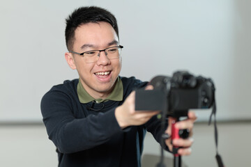 A happy Chinese educator smiles while preparing to record an online lesson, perfect for online education, distance learning, or educational technology concepts.
