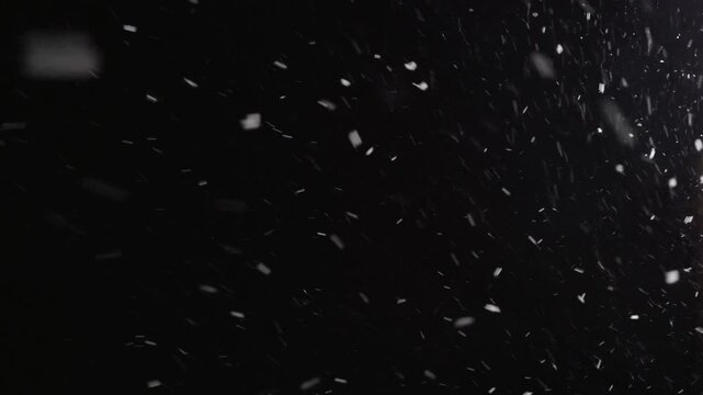 Street light illuminating falling snow during snowstorm at night. Realistic falling snow effect against a dark night sky, ideal for compositing winter scenes, creating a serene and magical atmosphere.
