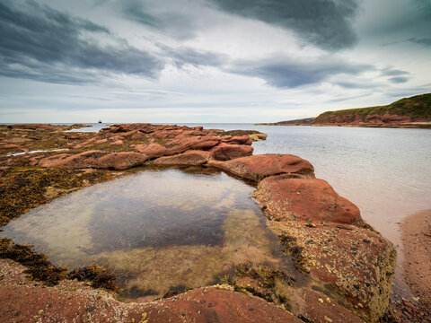 Fraserburgh rocky shore with low tide pools under cloudy sky