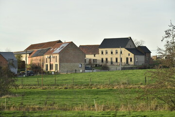 Obraz premium Lumière du coucher de soleil sur les fermes et maisons récents à Ghislenghien (Ath)