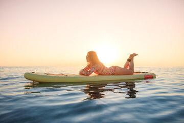 Young woman walking on stand up paddle sup boards by the sea during summer vacation