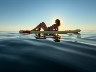 Young woman walking on stand up paddle sup boards by the sea during summer vacation