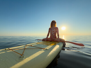 Young woman walking on stand up paddle sup boards by the sea during summer vacation