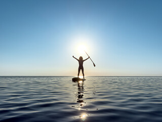 Young woman walking on stand up paddle sup boards by the sea during summer vacation