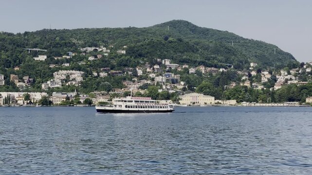 Passenger boat on Lake Como with Villa Olmo and green mountains in background
