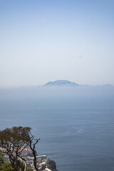 Jebel Musa Mountain Rising Above the Clouds, viewed from Gibraltar across the Strait of Gibraltar. Vertical Scenery of African Coastline emerging through Mist over the Sea.