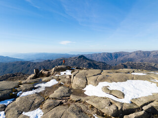 Hiker Man Standing on Granite Rocks and Mountains of Peneda-Geres National Park on Sunny Winter Day. Portugal. Aerial Drone Shot