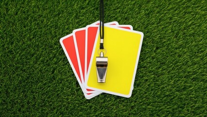 The Referee's Arsenal: A top-down perspective on a grassy field, displaying a collection of pivotal tools, including red and yellow cards alongside a whistle, signaling crucial moments within a game.