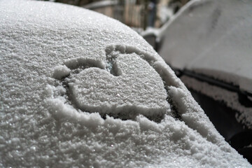 Valentine's Day concept: hand-drawn heart pattern on a frozen car windshield. Hand drawn heart shape on windshield of the car. Love symbol. Romantic background. A frozen windshield with a heart. 