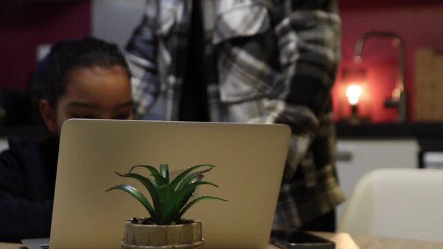 Worried dad overseeing his daughter while she uses a laptop, educating her on cybersecurity and online safety to shield her from internet risks like cyberbullying and unsuitable material