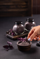 Hand flavoring gourmet purple sea salt with basil herbs