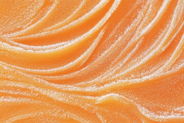 Close-up of smooth, creamy orange texture with soft waves and swirls. The surface appears glossy and inviting, resembling a dessert or cosmetic product.
