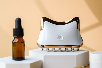 Brown glass dropper bottle with white jar and electronic face massager arranged on pedestals