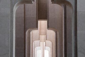 The view shows a series of concrete arches lined up in a modern structure. Light filters through the openings, creating interesting patterns on the walls
