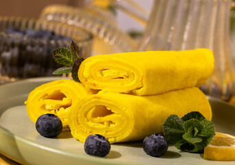 Yellow crepes rolled with blueberries and mint