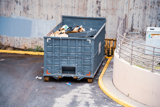 Large industrial dumpster filled with various types of trash and debris outdoors