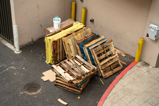 Stack of weathered wooden pallets and a white bucket in an urban alleyway