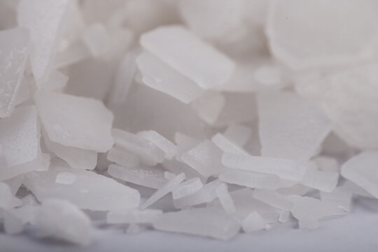 White salt flakes magnesium chloride macro background for spa wellness and chemical industry. Close-up of organic mineral crystals used for natural bath treatments and industrial de-icing agent