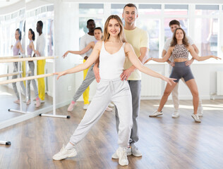 Fototapeta premium Energy guy and young woman are dancing classic version of waltz in couple during lesson at studio. Leisure activities and physical activity for positive people.