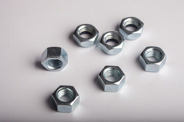 Assorted steel hex nuts on white background for industrial hardware supply and mechanical engineering. Various sizes of metallic fasteners for bolt security construction and technical assembly