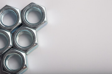 Assorted steel hex nuts on white background for industrial hardware supply and mechanical engineering. Various sizes of metallic fasteners for bolt security construction and technical assembly