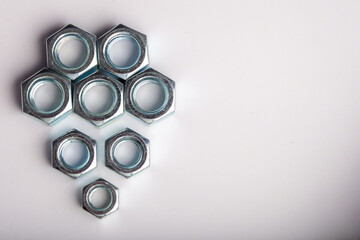 Hexagonal steel nuts macro industrial hardware group for mechanical engineering and construction projects. Close-up of silver metallic fasteners used for secure bolt connection and assembly