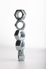 Steel hex nuts stack tower on white background for industrial business concept and construction balance. Vertical row of metallic fasteners representing strength stability and engineering precision