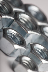 Assorted steel hex nuts on white background for industrial hardware supply and mechanical engineering. Various sizes of metallic fasteners for bolt security construction and technical assembly