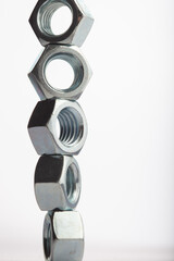 Steel hex nuts stack tower on white background for industrial business concept and construction balance. Vertical row of metallic fasteners representing strength stability and engineering precision