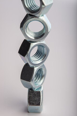 Steel hex nuts stack tower on white background for industrial business concept and construction balance. Vertical row of metallic fasteners representing strength stability and engineering precision