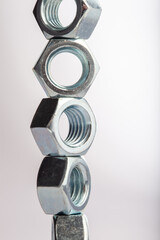 Steel hex nuts stack tower on white background for industrial business concept and construction balance. Vertical row of metallic fasteners representing strength stability and engineering precision