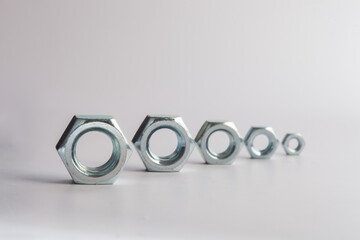 Hexagonal steel nuts macro industrial hardware group for mechanical engineering and construction projects. Close-up of silver metallic fasteners used for secure bolt connection and assembly