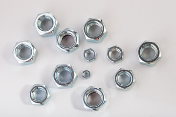 Assorted steel hex nuts on white background for industrial hardware supply and mechanical engineering. Various sizes of metallic fasteners for bolt security construction and technical assembly