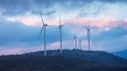 Silhouettes of wind turbines on hike in blue hour in the morning with cloudy sky © sergejson