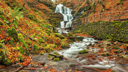 wide angle view to waterfall in national park with stone pathway to it and creek on foreground