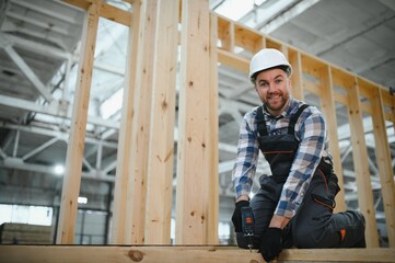 Fototapeta premium Construction of modular houses. Male construction worker in uniform and hard hat at construction site
