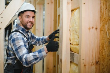Portrait of a carpenter smiling with crossed arms in a lumber warehouse, showcasing expertise in the modular building industry