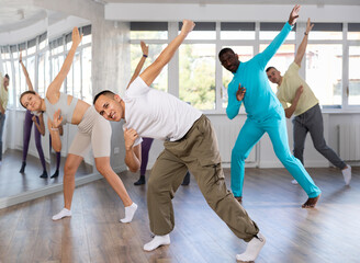 During dance workshop, European guy with team of like-minded multinational people learn to perform elements of energy hip hop dance. Studio school for amateur and professional dancers