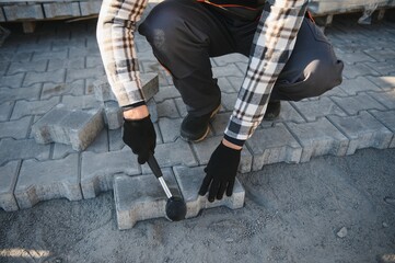 The master in gloves lays paving stones in layers. Garden brick pathway paving by professional...