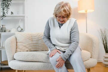 Obraz premium Arthritis symptoms. Woman suffering from pain in knee at home