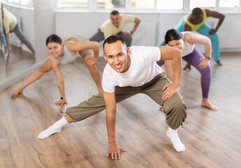 During dance workshop, European guy with team of like-minded multinational people learn to perform elements of energy hip hop dance. Studio school for amateur and professional dancers