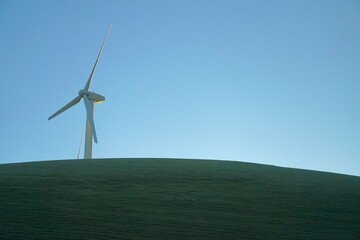 Obraz premium Wind turbine overlooking a shadowed hill