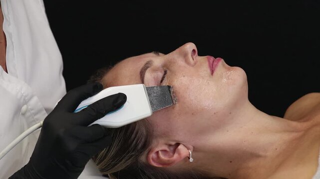 Professional cosmetologist performing a modern facial skincare procedure on a woman in a clinical spa environment. Beauty technology, hygiene standards, relaxation, and professional skin treatment 