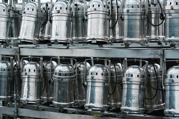 Industrial stainless steel milk containers on automated production line. Modern dairy manufacturing...
