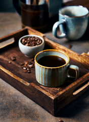 Cup of black coffee and coffee beans on a wooden tray