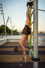 Urban athlete performing a handstand on an outdoor bar