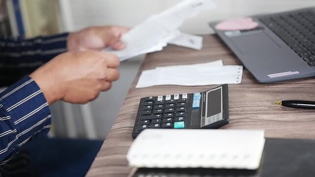 An accountant reviews receipts. Accounting concepts and financial literacy. A person reviews a stack of checks and paper receipts. Excessive, irrational, and reckless spending. Financial problems. Fin