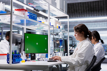 Green screen PC used by scientist in laboratory to process DNA patient data for clinical research. Research facility professional uses mockup computer to do lab genetic analysis diagnostics