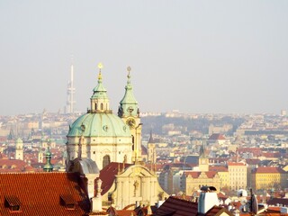 Obraz premium Prague Cityscape with Historic Church and Red Roofs at Sunset.